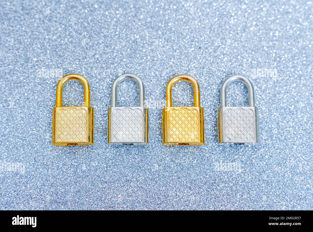 Vier Stahlvorhängeschlösser auf glitzerndem Hintergrund. Stockfoto