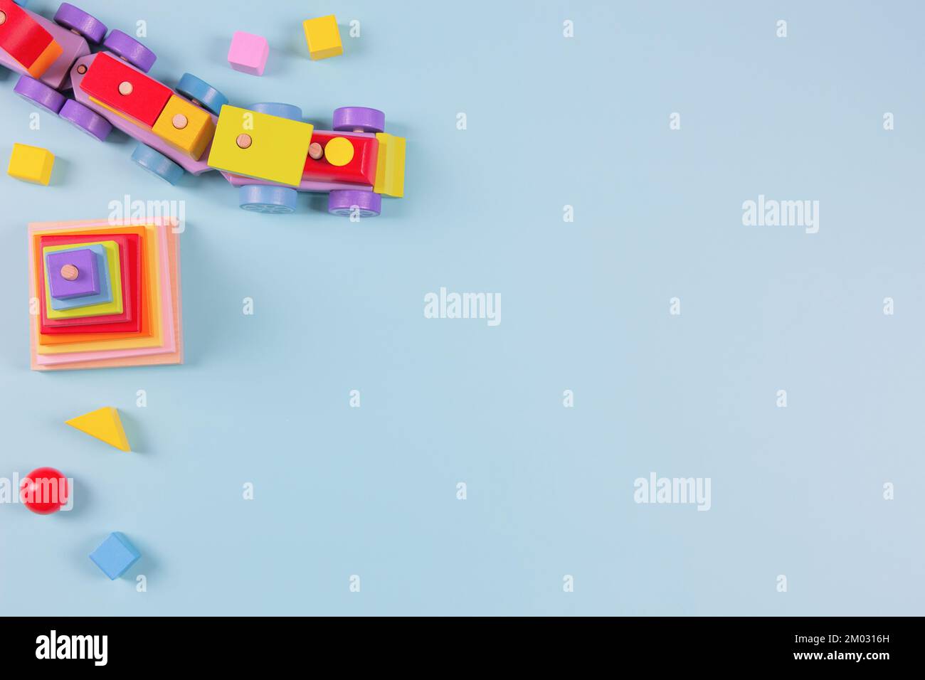 Hintergrund für Kinderspielzeug. Holzzug, farbenfrohes, nachhaltiges Lernspielzeug auf hellblauem Hintergrund. Montessori, umweltfreundliches Kinderspielzeug Stockfoto