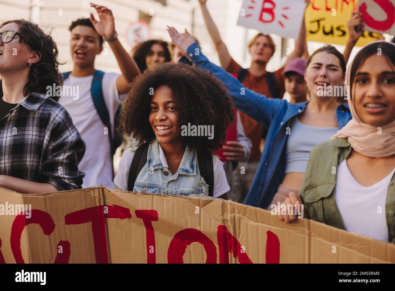 Klimaaktivismus der Z-Generation. Junge Menschen halten ein Banner und marschieren gegen den Klimawandel. Multikulturelle Jugendaktivisten, die für Clim kämpfen Stockfoto
