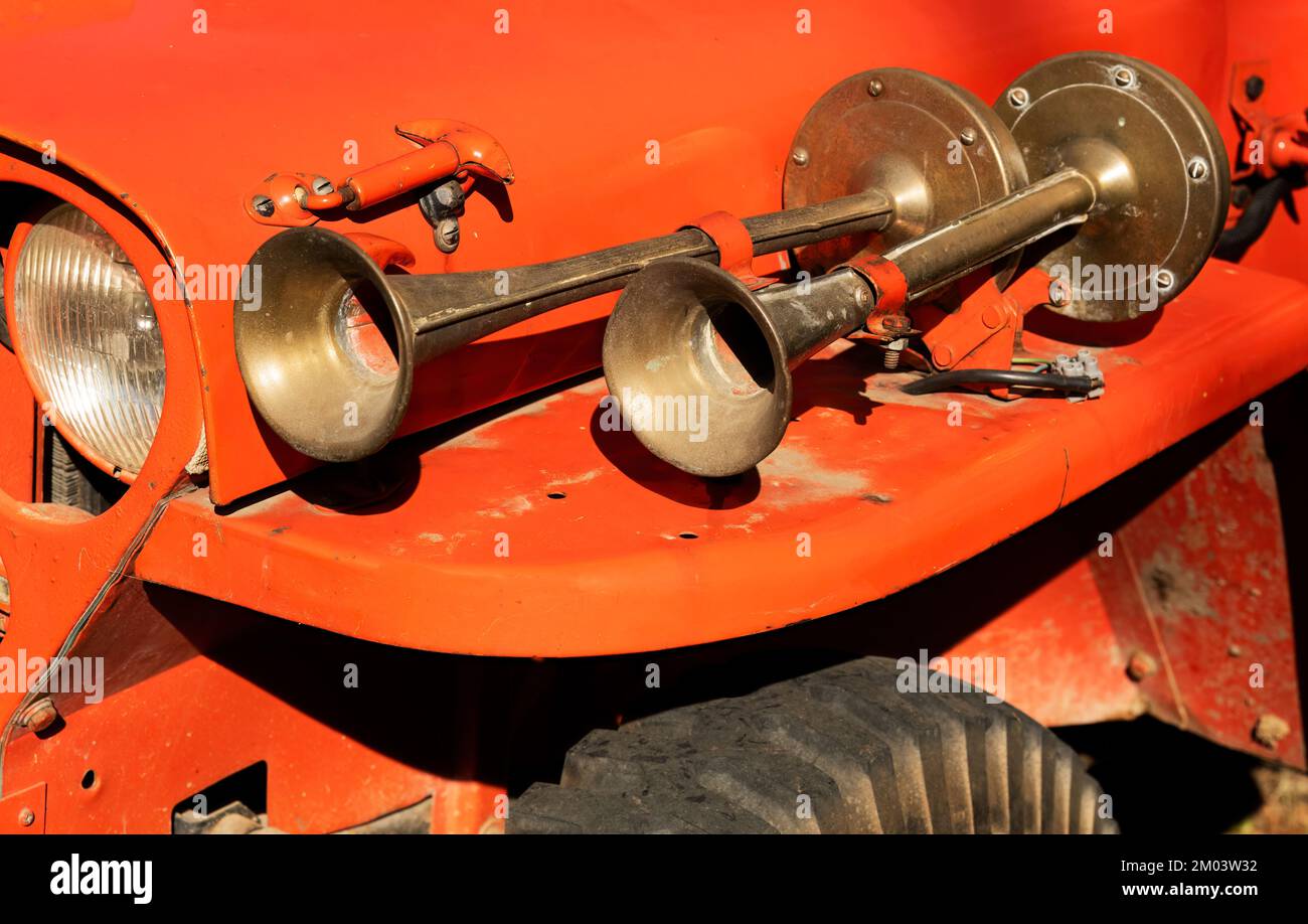 Drucklufthörner aus altem Messing an der Karosserie eines roten Lkws. Stockfoto