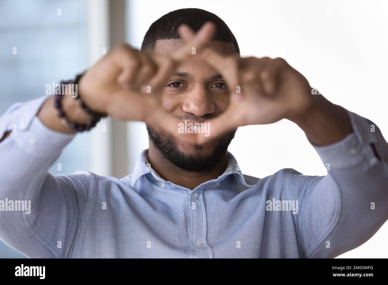 Ein glücklicher junger Afrikaner, der durch einen Finger-Fotografierahmen schaut Stockfoto