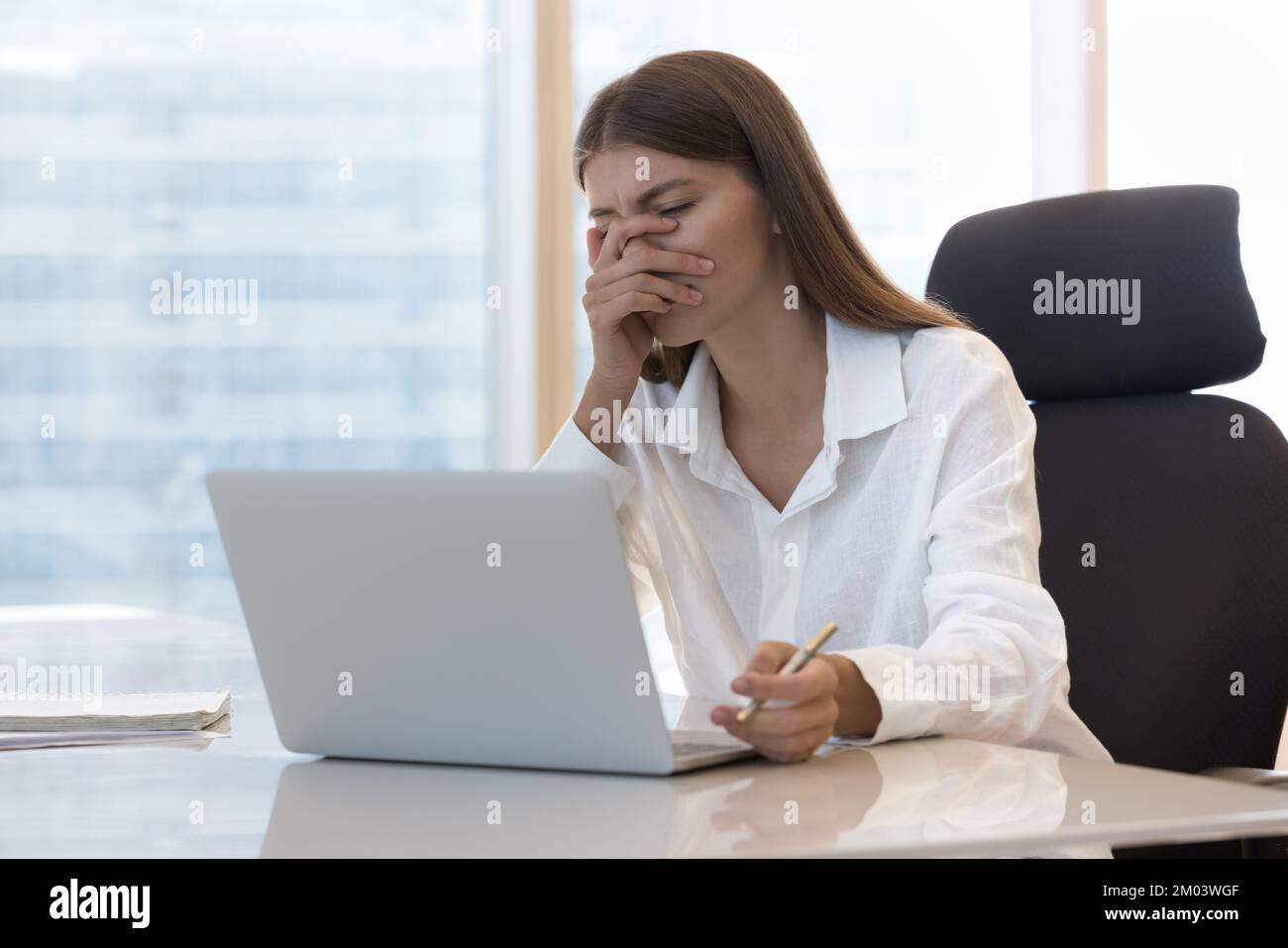 Müde, frustrierte Büroangestellte, die Probleme mit dem Laptop hat Stockfoto