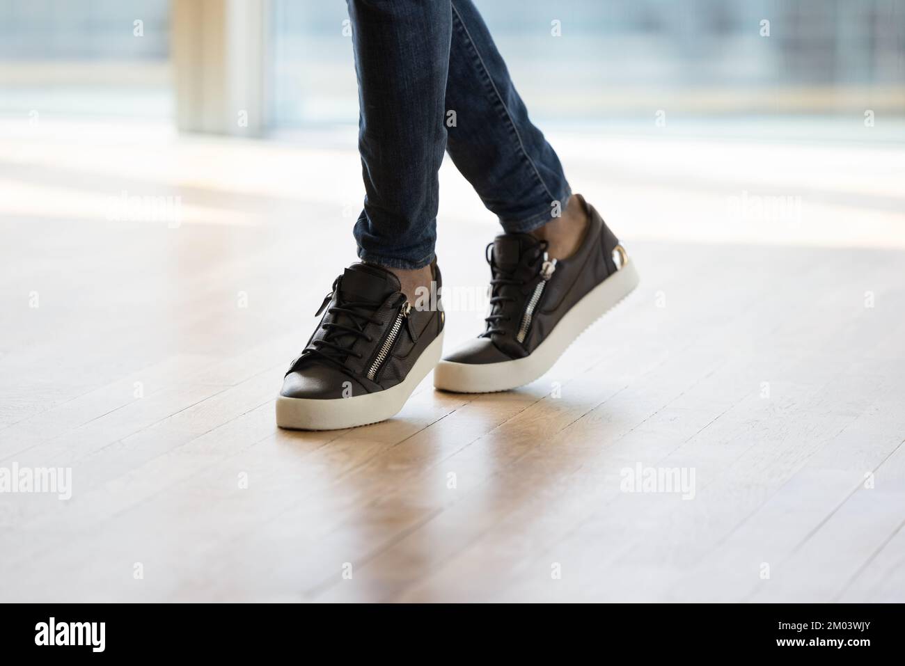 Beine und Füße in trendigen, stylischen Sneakern junger Männer Stockfoto