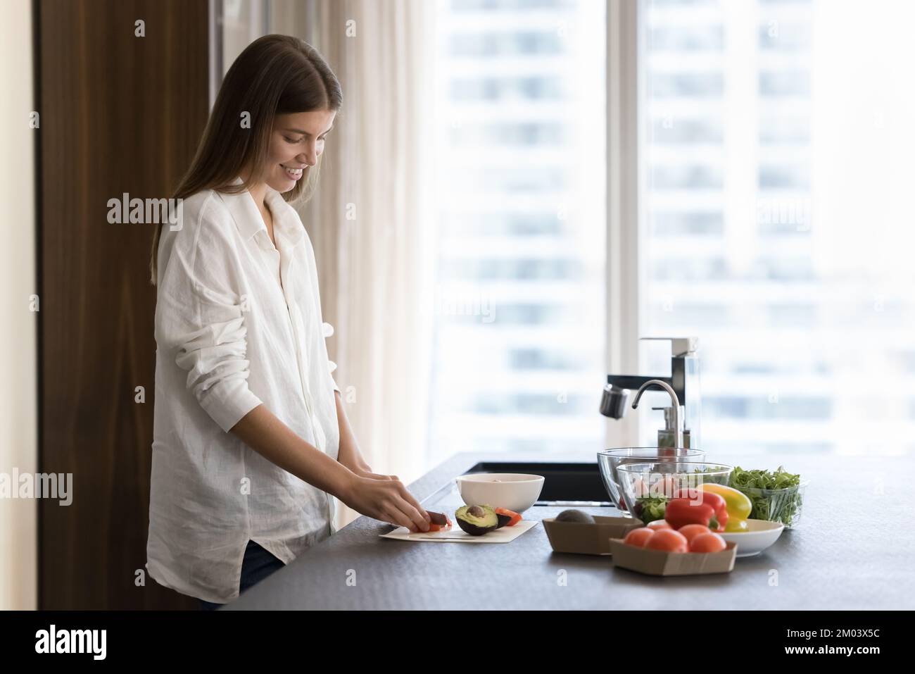 Positives, hübsches Koch-Blogger-Mädchen, das Salat in der Küche zubereitete Stockfoto