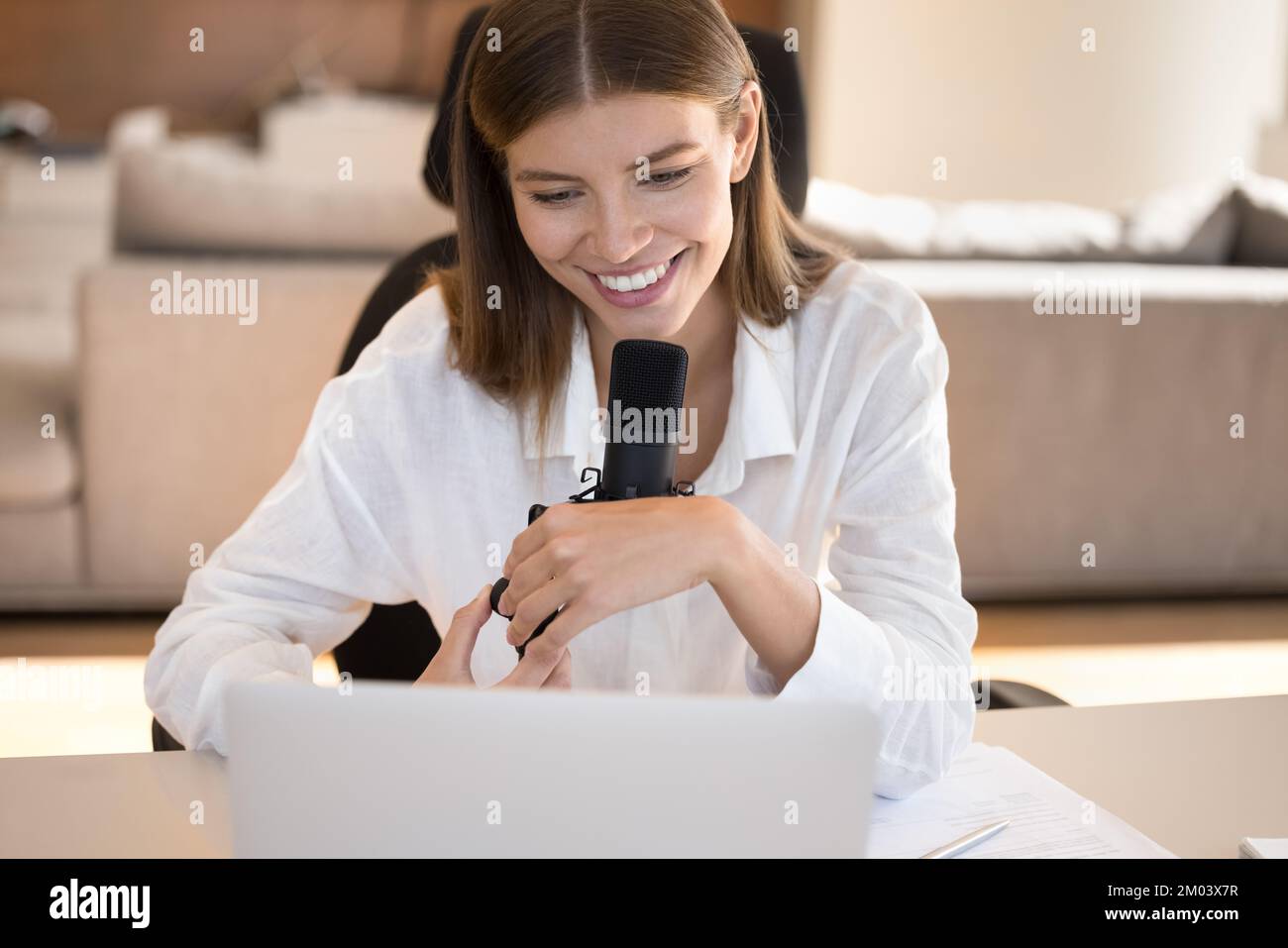 Glückliches, hübsches, junges Bloggermädchen, das vor einem großen professionellen Mikrofon spricht Stockfoto