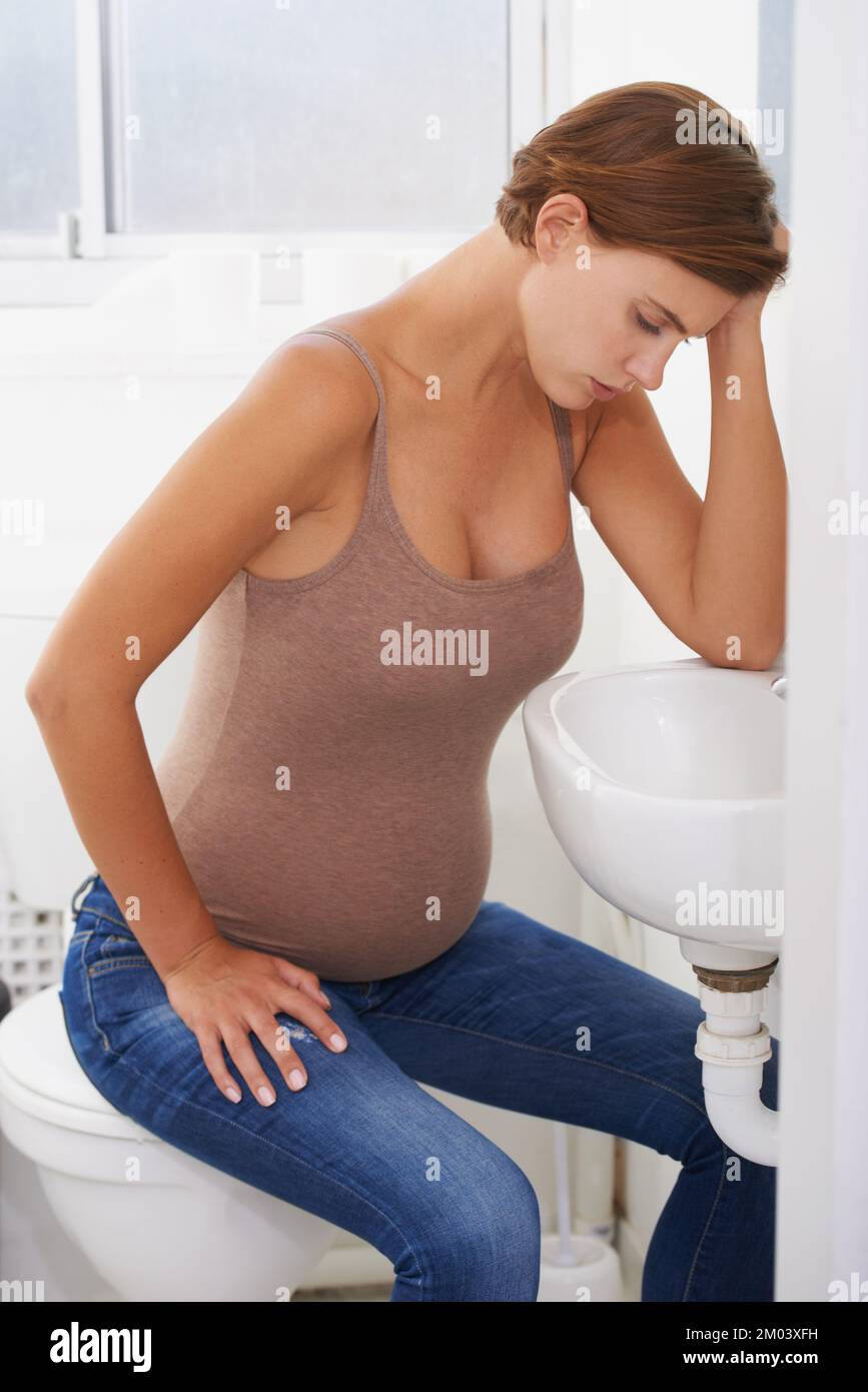 Die Versuche, Mutter zu werden. Eine schwangere Frau, die mit Morgenkrankheit im Bad kämpft. Stockfoto
