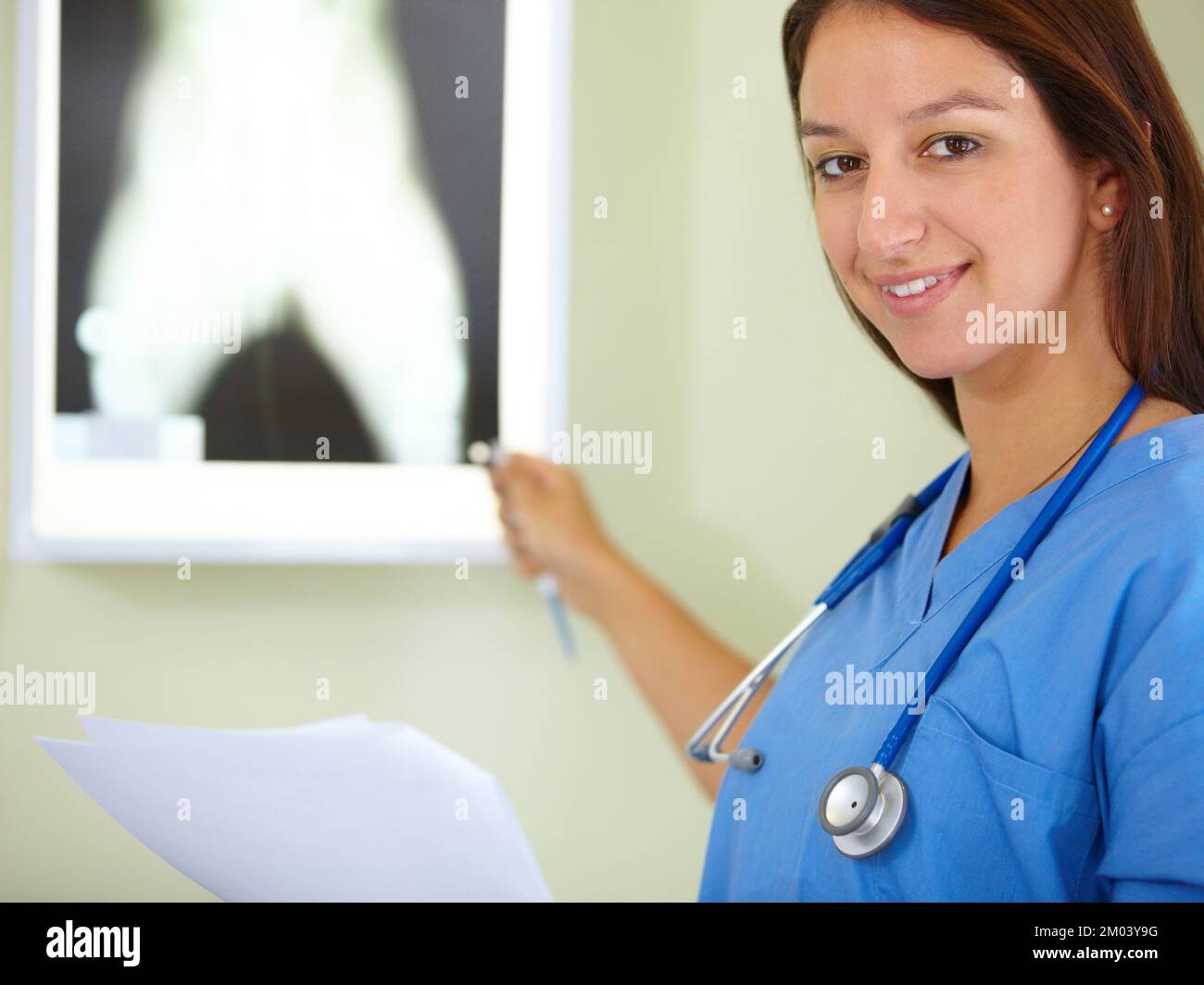 Ich vertraue meiner Arbeit. Porträt einer jungen Frau in Kittel, die auf ein Röntgenbild zeigt. Stockfoto