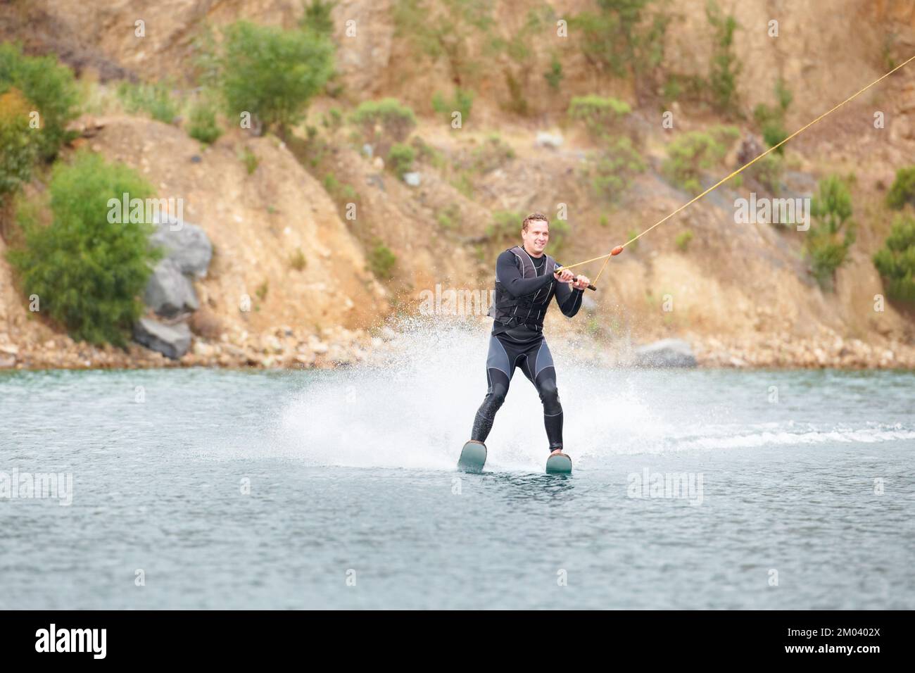 Er hat tolle Techniken. Abenteuerlustiger junger Mann beim Wasserski auf dem See. Stockfoto
