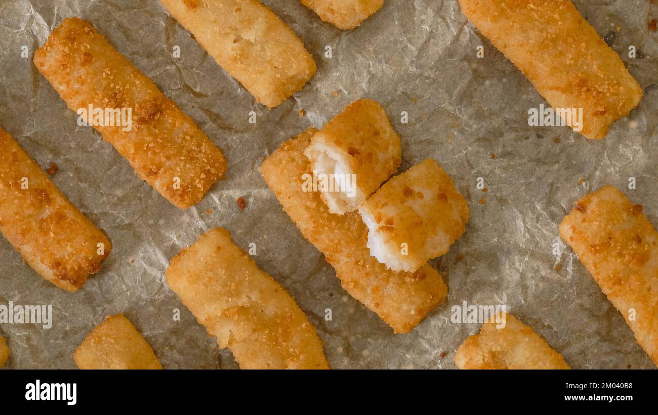Knusprige panierte Fischstäbchen aus wild gefangenem Alaska-Pollock aus der Nähe auf einer Backpfanne, direkt aus dem Ofen, flach liegend Stockfoto