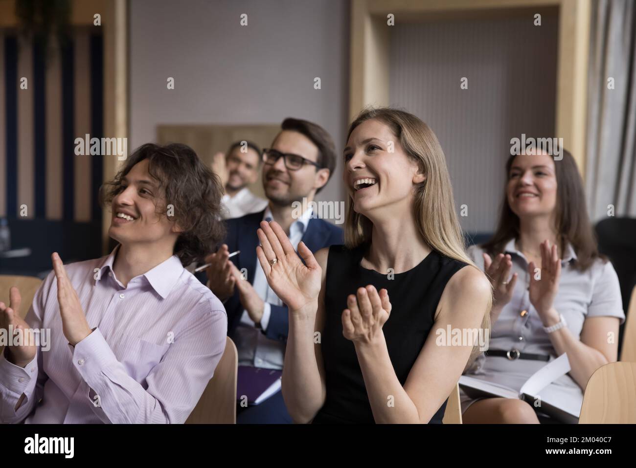 Eine Gruppe lächelnder Geschäftsleute, die den Corporate Trainer begrüßen Stockfoto