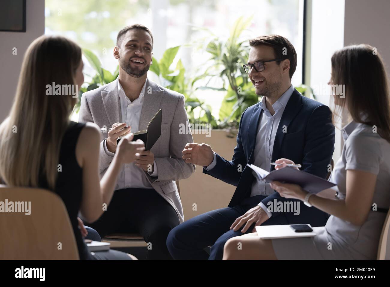 Vier professionelle Teamkollegen der Millennials lösen ihre Geschäfte in Briefing-Sitzungen Stockfoto