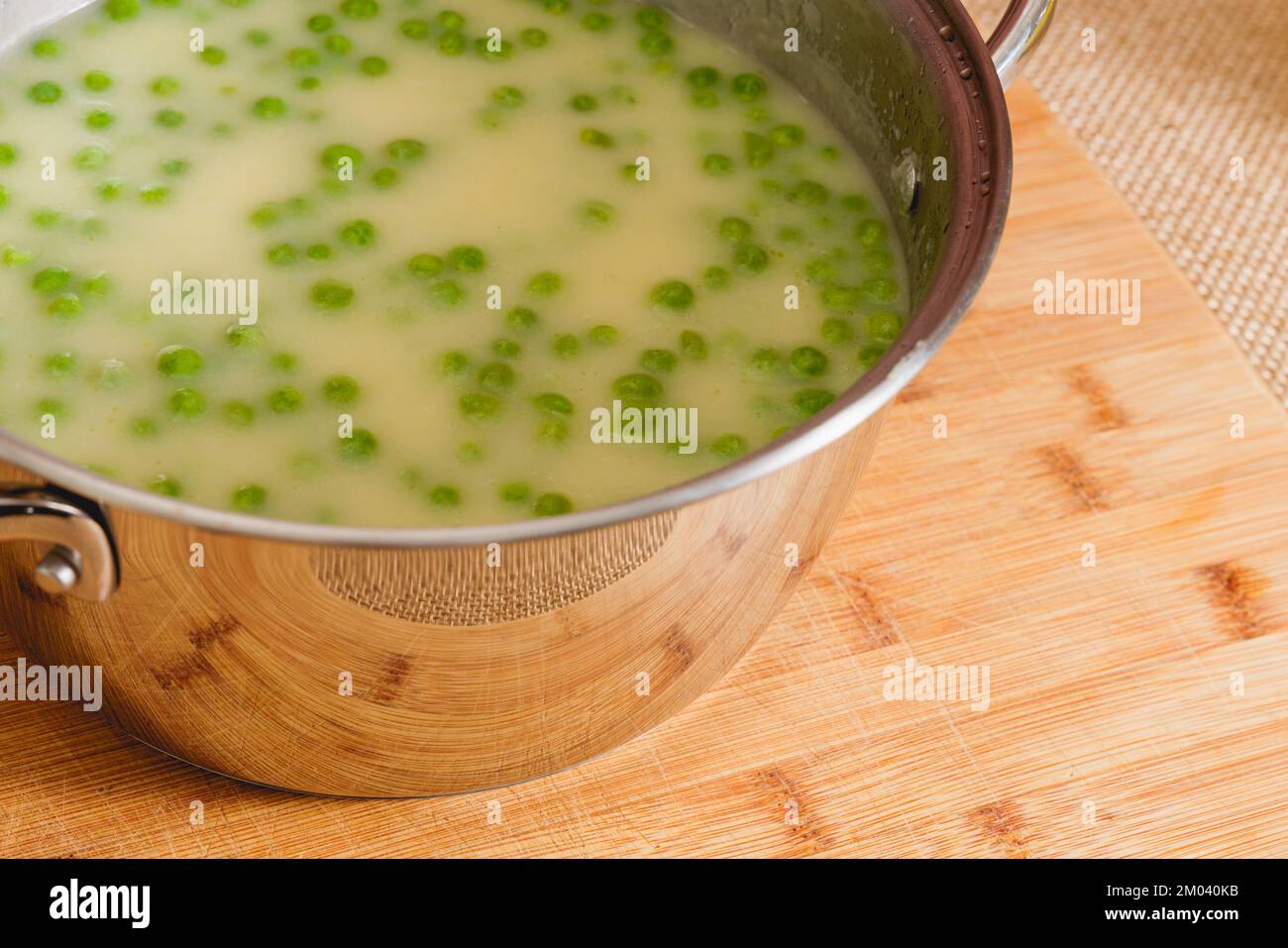 Cremiges Sellerie-Suppenpüree mit grüner Erbse in einer Kochpfanne, Nahaufnahme auf dem Küchentisch Stockfoto