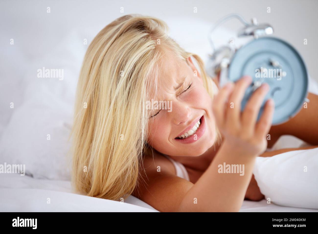 Nein, ich brauche eine Schlummertaste. Verärgerte Frau, die ihren Wecker hält, mit einem Ausdruck der Frustration. Stockfoto