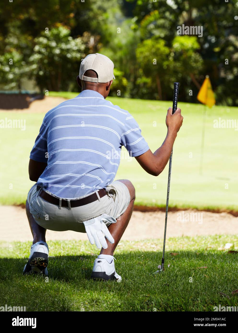 Ein harter Chip über dem Bunker. Rückansicht eines Golfers, der einen langen Chip bis ins Grün sieht. Stockfoto