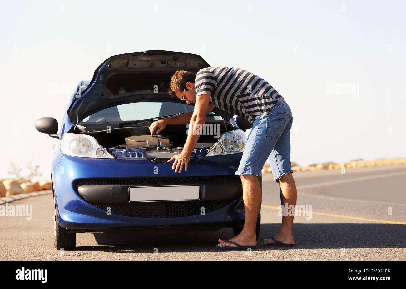 Ich finde den Weg, um seinen Freund zu reparieren. Ein junger Mann, der versucht, sein kaputtes Auto am Straßenrand zu reparieren. Stockfoto
