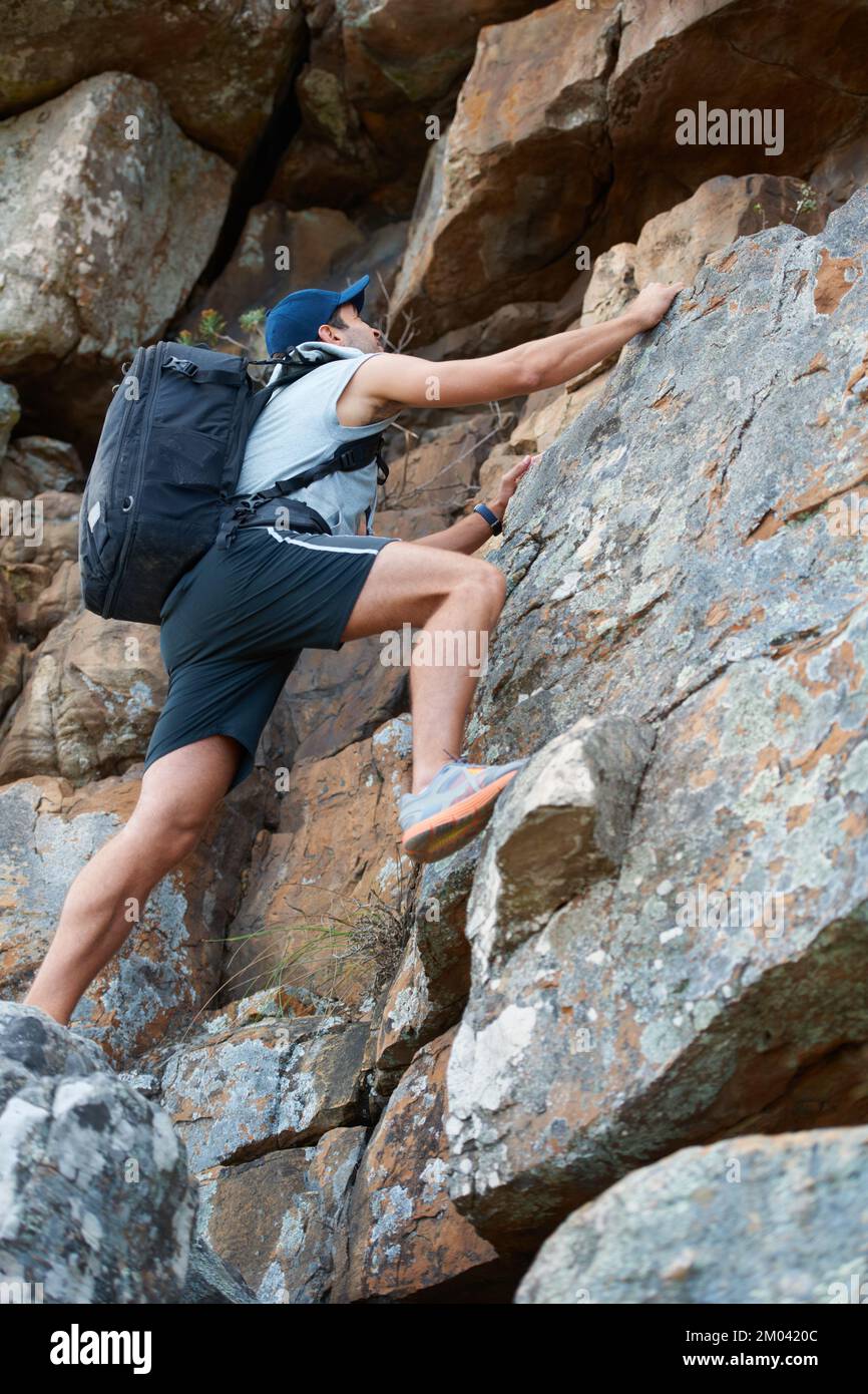 Er hat einen sicheren Griff. Junger Bergsteiger, der ein Felsgesicht erklingt. Stockfoto