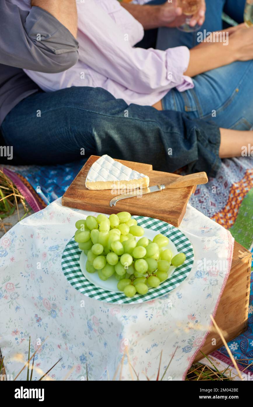 Nichts ist romantischer als ein Picknick. Ein liebevolles Paar, das zusammen ein gemütliches Picknick auf einem malerischen Feld genießt. Stockfoto