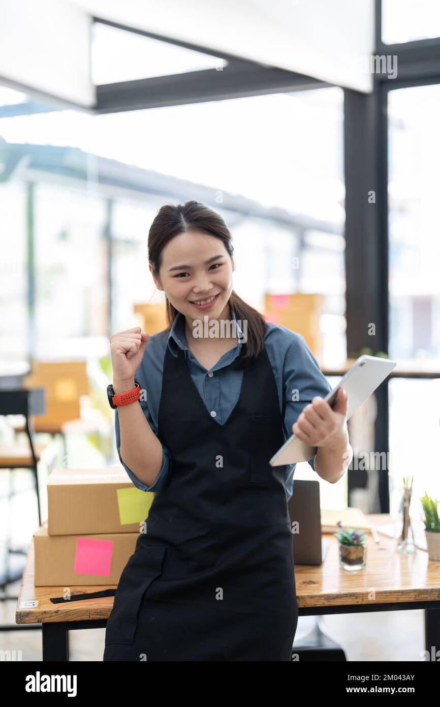 KMU-Unternehmer kleine Unternehmer Online-Verkaufsideen, Happy Young asiatischer Unternehmer arbeitet an Computer und einer Box zu Hause, Lieferung Stockfoto