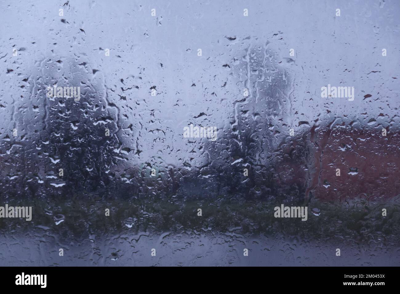 Regen Sie Tropfen auf das Fenster mit einem Hintergrund, der nicht scharf ist Stockfoto