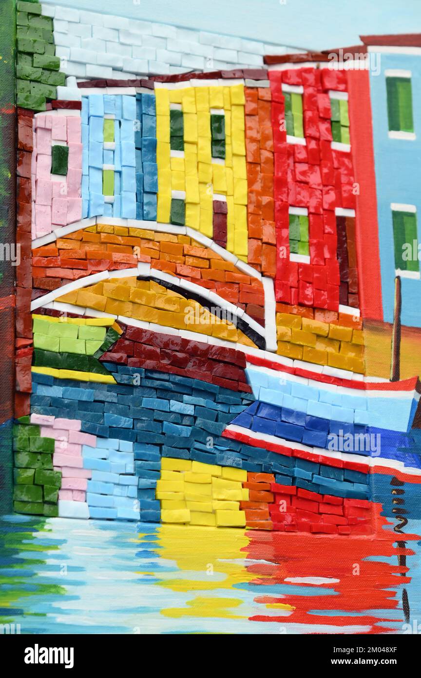 Farbenfrohes Mosaik aus hellen Häusern mit Kanal und Brücke an einer Ziegelwand an der Straße Stockfoto