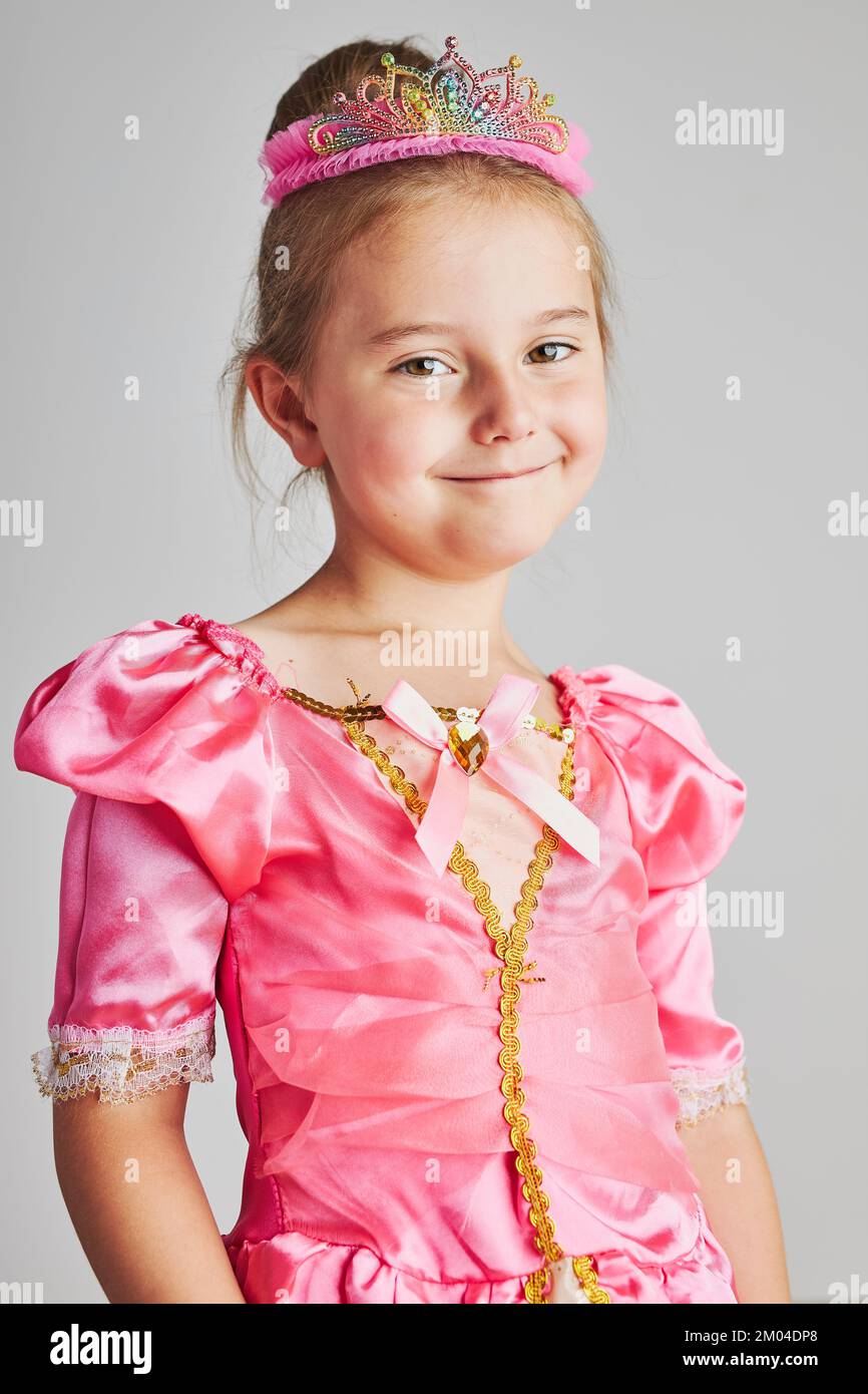 Kleines Mädchen genießen ihre Rolle der Prinzessin. Liebenswert niedlichen 5-6 Jahre altes Mädchen trägt rosa Prinzessin Kleid und Tiara auf schlichtem Hintergrund stehen Stockfoto