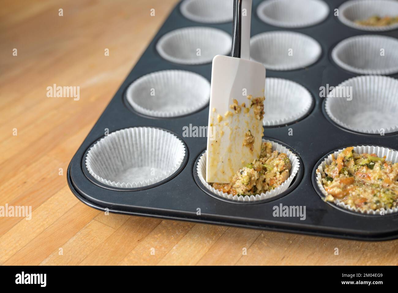 Füllung einer Mischung aus Gemüse und Ei in einem Muffin Backblech für herzhafte Cupcakes, gesunde vegetarische kohlenhydratarme Diät, ausgewählter Fokus, enge Tiefe von Stockfoto