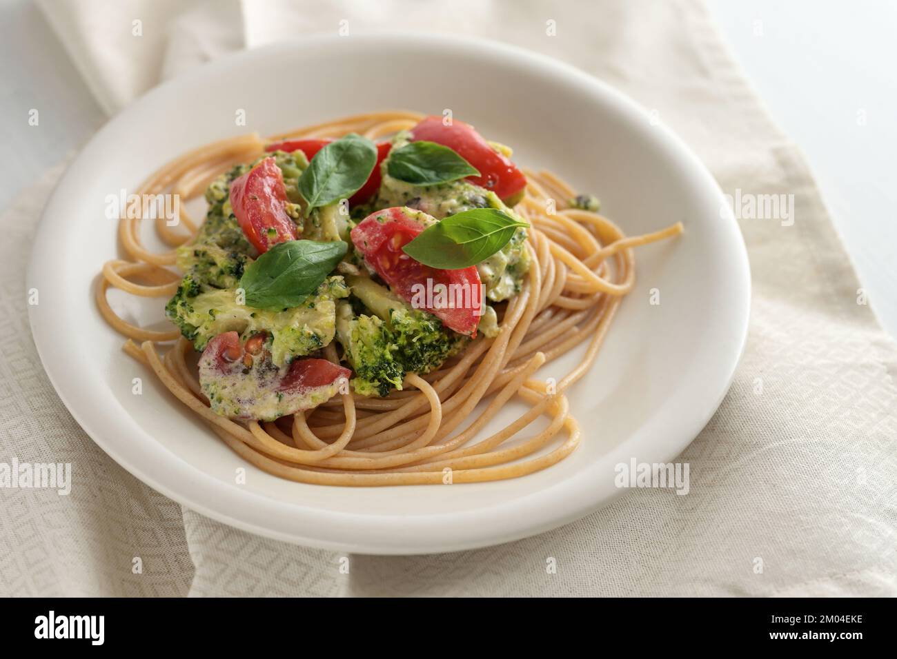 Vollkornspaghetti mit Brokkoli und Tomatensoße und Basilikumgarnierung, gesunde vegetarische hausgemachte Küche, ausgewählter Fokus, kleine Tiefe des Tortes Stockfoto