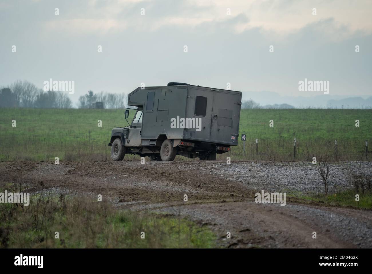Britisches Militär Land Rover Defender Wolf Medizinische Hilfe Leichtes Nutzfahrzeug, das sich auf einer Schlammstrecke auf einer Militärübung, Wiltshire UK, bewegt Stockfoto