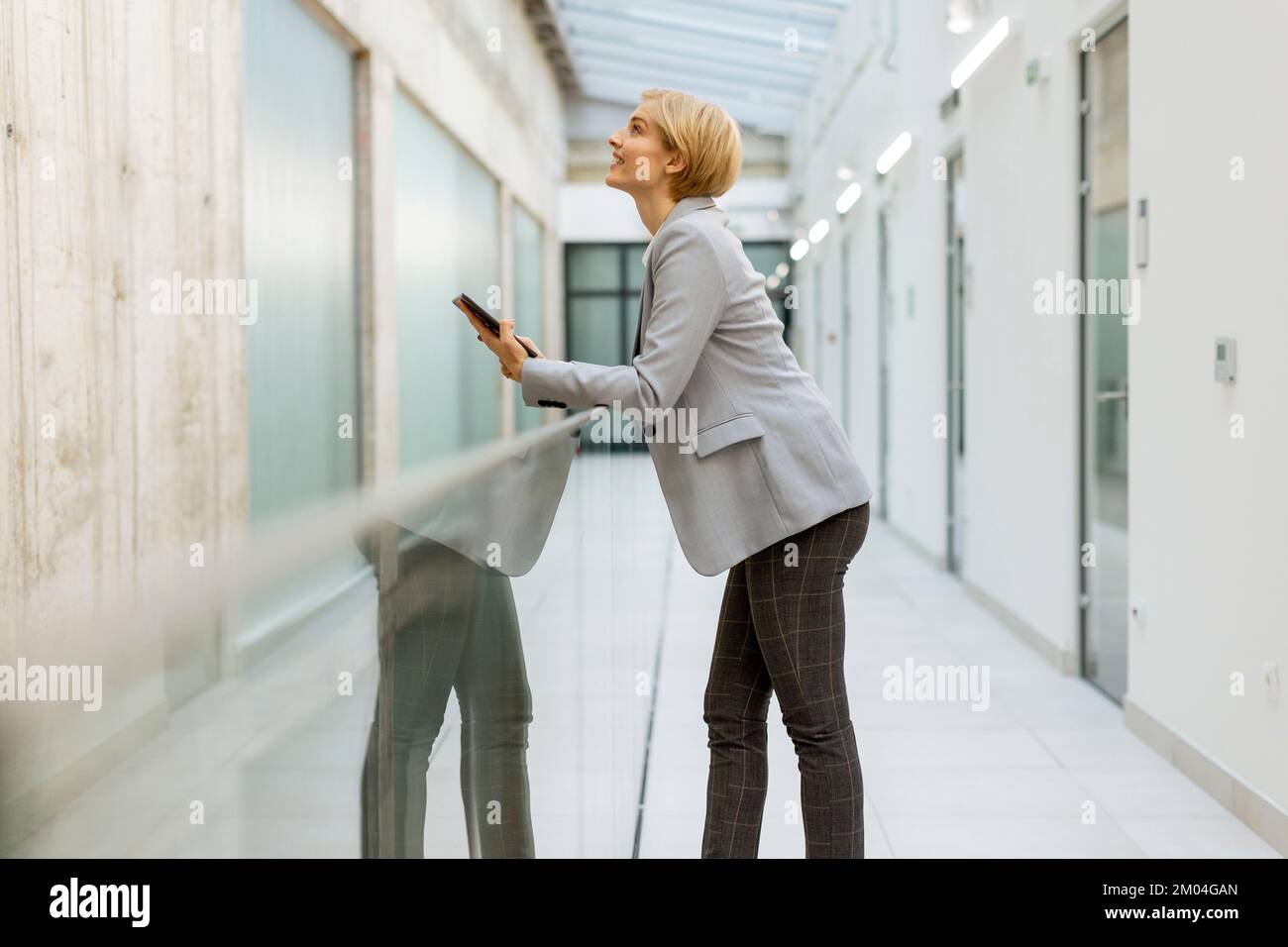 Geschäftsfrau, die ein digitales Tablet im modernen Büroflur verwendet Stockfoto