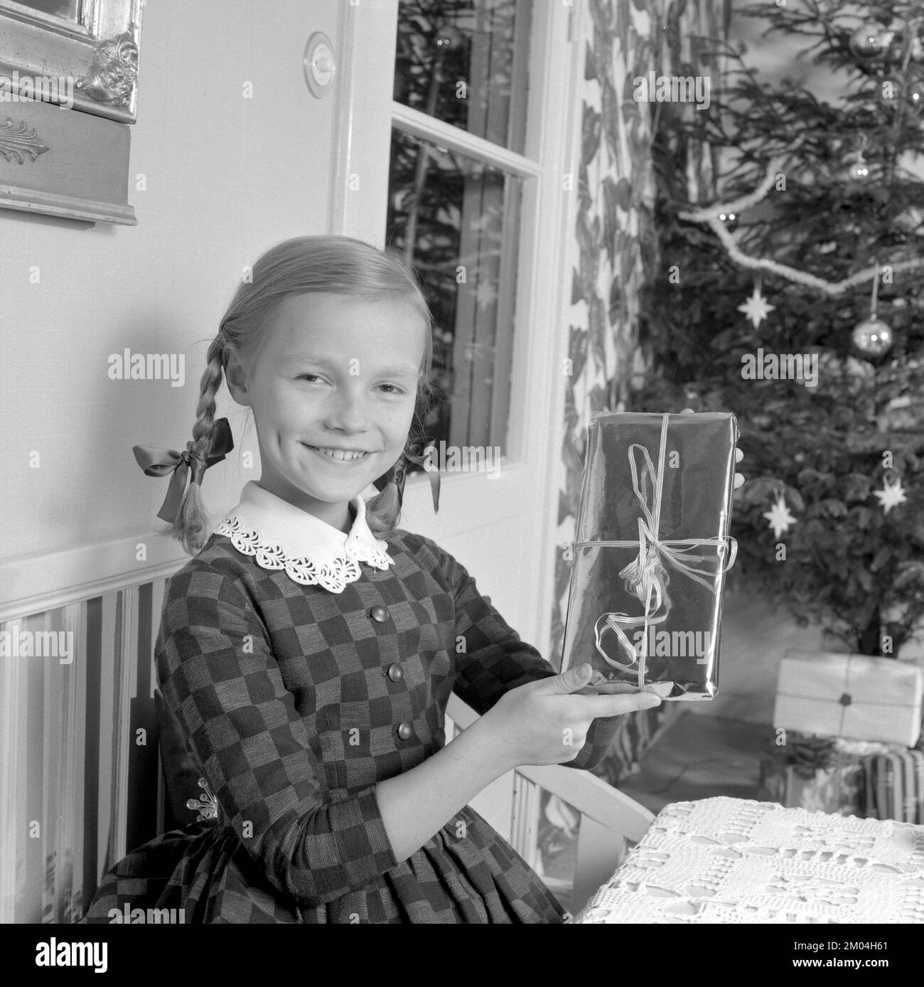 Weihnachten in den 1960er. Ein junges Mädchen hat ein schönes, verpacktes weihnachtspaket. Schweden 1963 Ref. 4827 Stockfoto