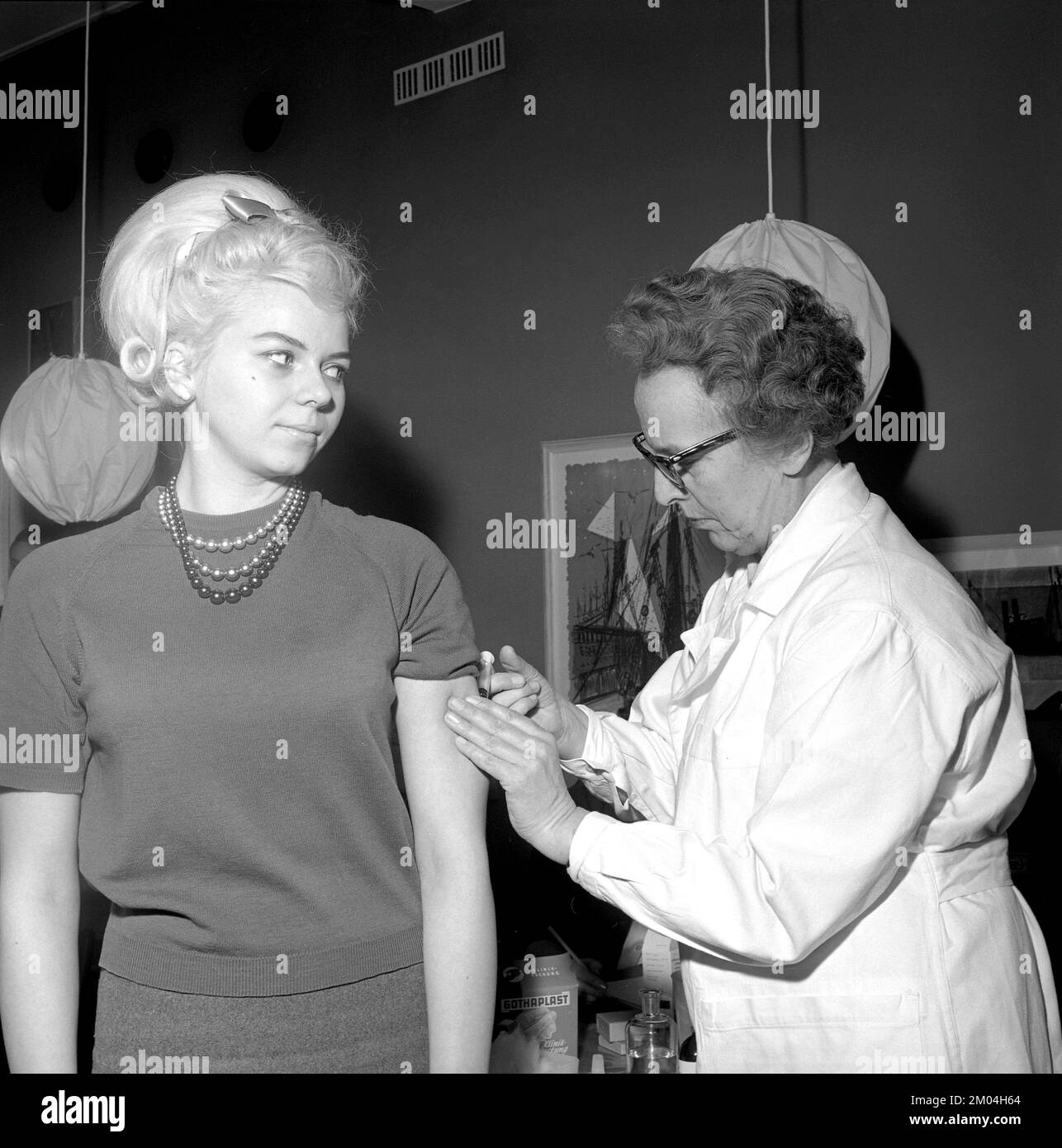 Impfstoff in den 1960er Jahren. Eine Krankenschwester injiziert einer jungen Frau einen Impfstoff in den Arm. Schweden 1965 Conard Ref 5011 Stockfoto