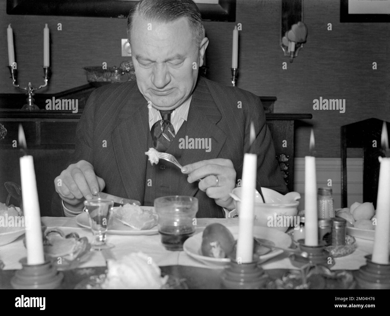 zu weihnachten in den 1940er. Ein Mann isst zu weihnachten, und seinem Gesichtsausdruck nach ist das Gericht nicht nach seinem Geschmack. Schweden dezember 1940 Kristoffersson 42-8 Stockfoto