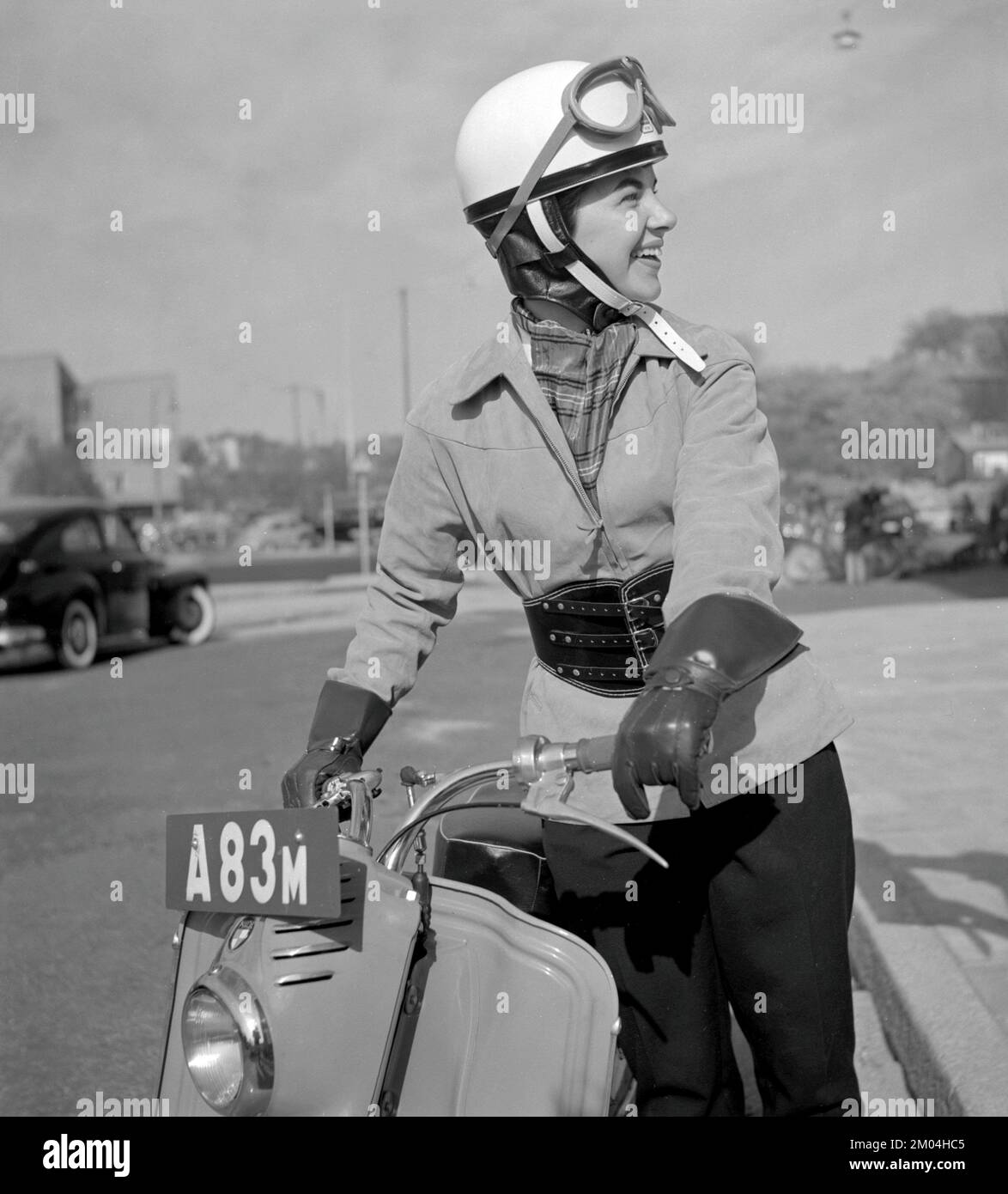 In den 1950er Jahren. Eine junge Frau, die auf einem deutschen Puch-Roller gesehen wurde. Die Fahrerin trägt die typische Motorradbekleidung und Accessoires des Jahrzehnts, Helm, Jacke, Nierengurt und Handschuhe. Schweden 1955 Stockfoto