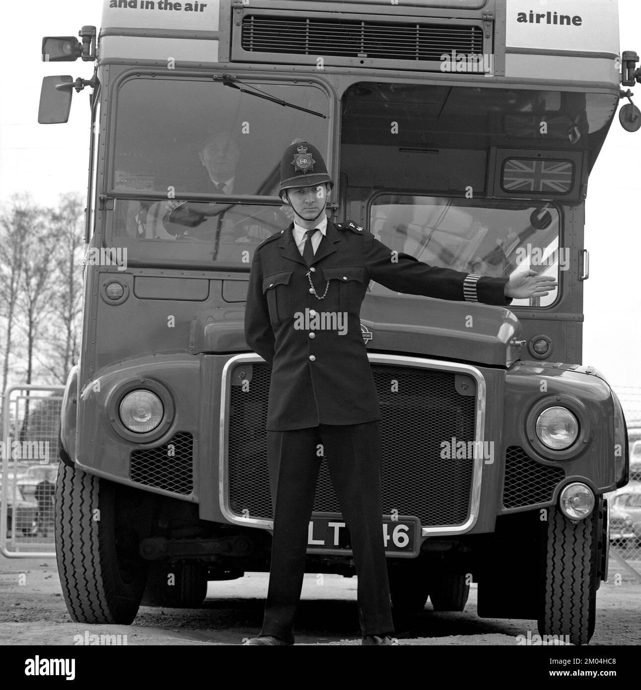 Ein bobby in den 1960er zu sein. Die britische Ausstellung in Stockholm vom 18. Mai bis 3. juni 1962, auf der über 500 britische Unternehmen ihre Produkte vorstellten. Ein Mann in britischer Polizeiuniform ist vor einem Doppeldeckerbus abgebildet, der mit seiner Hand ein Schild macht. Schweden 1962 Stockfoto
