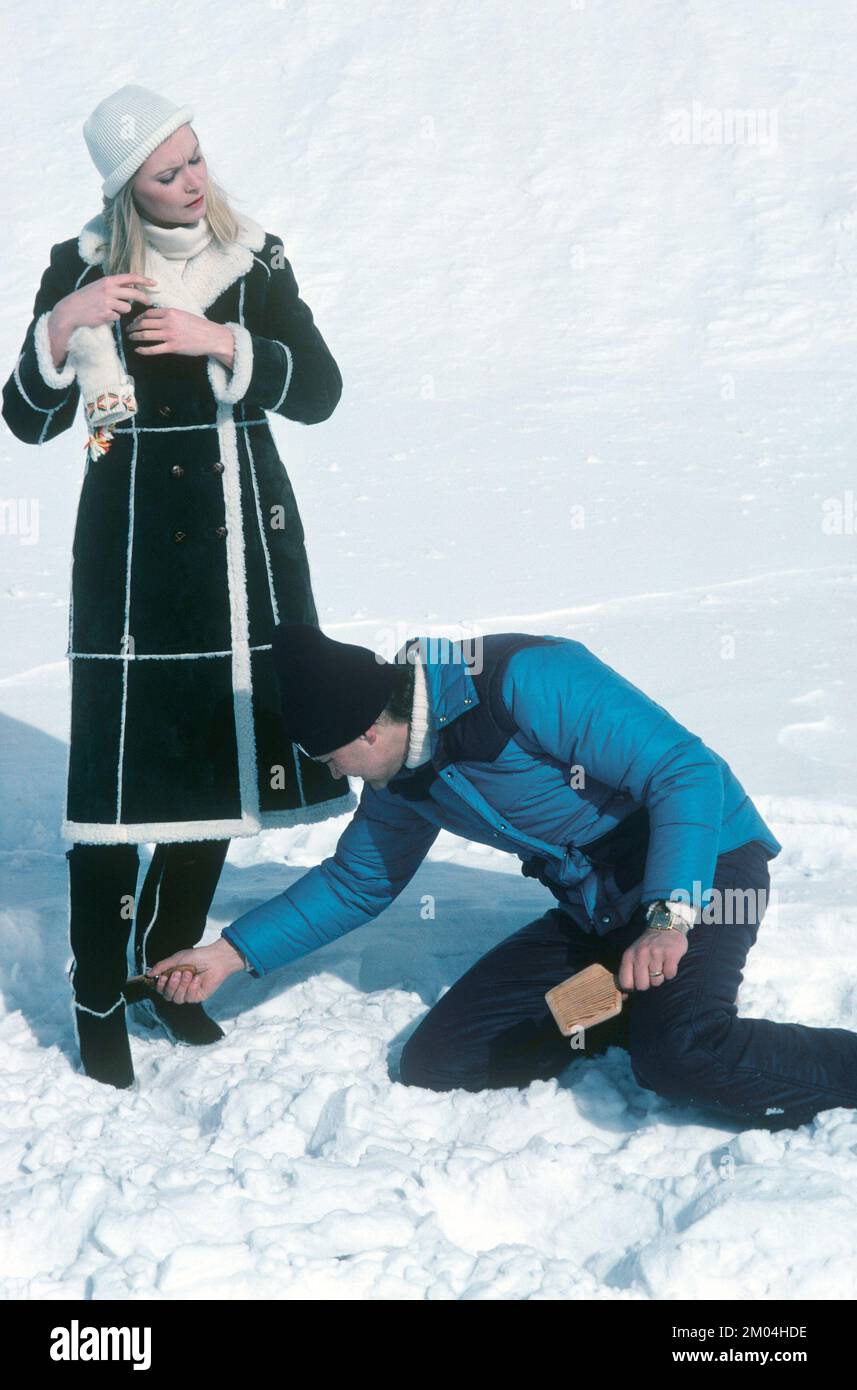 Mode in den 1980er Jahren. Ein junges Model wird für ein Fotoshooting vorbereitet. Sie trägt die Wintermode der Jahre, eine warme Mantel-Handmütze. Es wird ein Assistent angezeigt, der die Details fertigstellt. Schweden märz 1980 Stockfoto