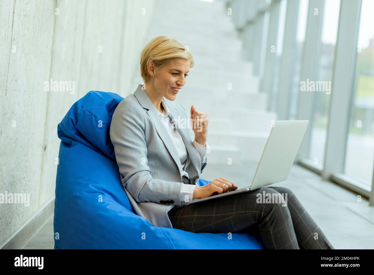 Geschäftsfrau, die an einem Laptop in einer Faultüte im modernen Büro arbeitet Stockfoto