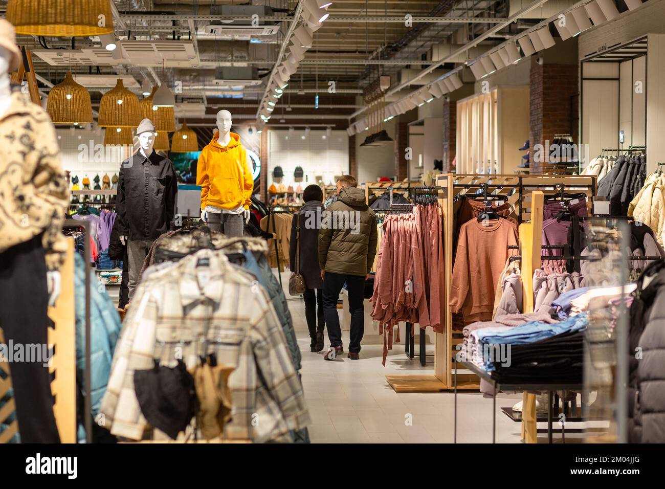 Ein unbekanntes Paar von Kunden, die Kleidung in einem modernen Bekleidungsgeschäft wählen. Einkaufskonzept. Stockfoto