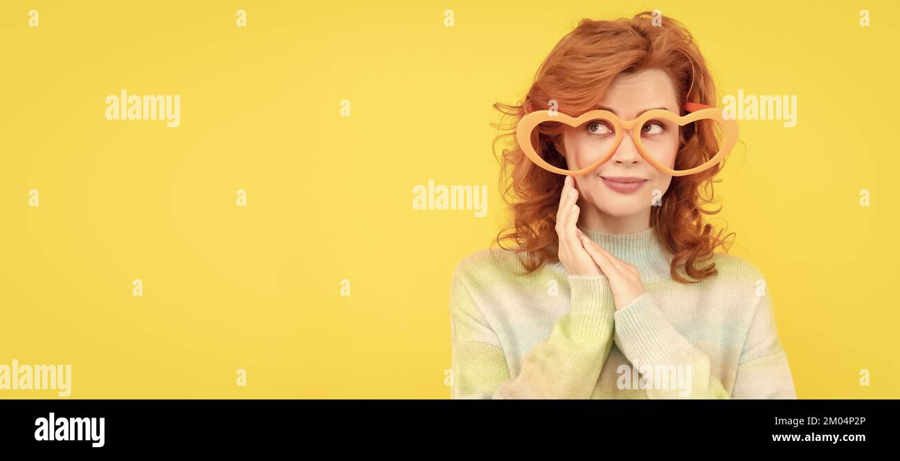 Frau isoliert Gesicht Porträt, Banner mit Kopieplatz. Glücklich Rotschopf Frau tragen lustige Party-Brille auf gelbem Hintergrund, Partei. Stockfoto
