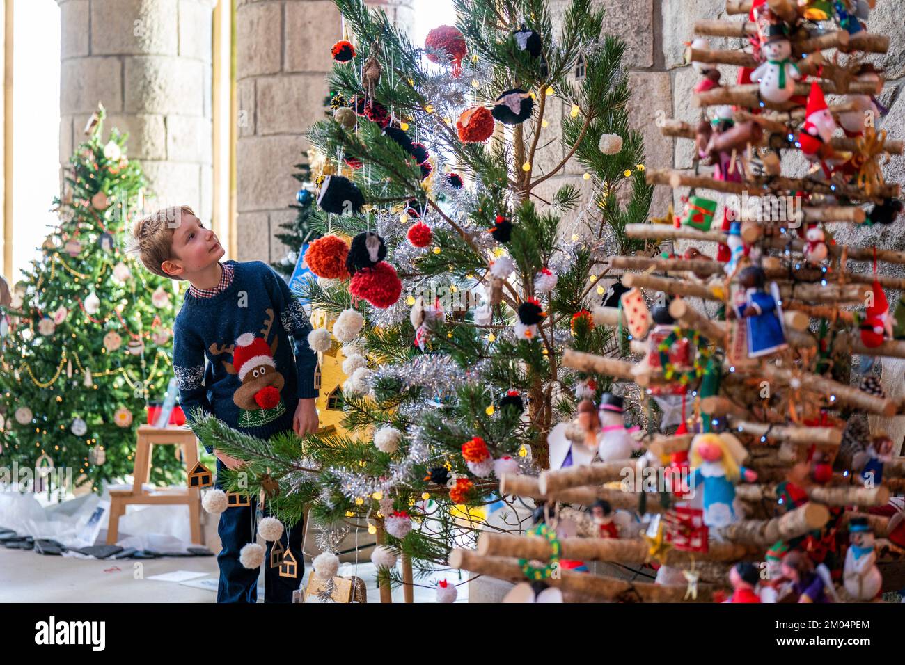 Im Alter von 8 Jahren blickt Robert Hodge auf einige der 63 Bäume während des jährlichen Christmas Tree Festival in Saint Conan's Kirk, Lochawe in Argyll. Mitglieder der Gemeinde, Schulgruppen und Wohltätigkeitsorganisationen spenden, erstellen und dekorieren Bäume für die Veranstaltung, damit Menschen am Erbe des kirk teilhaben können. Foto: Sonntag, 4. Dezember 2022. Stockfoto