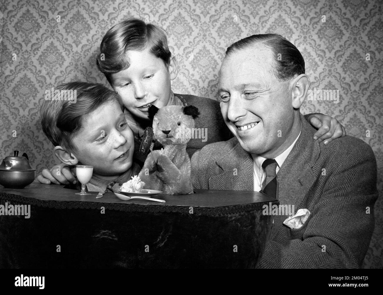 Foto von Harry Corbett mit Sooty and Sons David, 9 auf der linken Seite, und Peter (besser bekannt als Matthew Corbett), 6 Jahre alt. Datum: 8/2/1955. Ruoty wird 2023 75 Jahre im Showbusiness feiern, wobei der aktuelle Wächter des unverwechselbaren Gelbbbären sagt, Einfachheit sei der Schlüssel zu seiner dauerhaften Beliebtheit. Sidekicks Sweep, Soo und Richard Cadell werden im nächsten Jahr zusammen mit Ruoty eine Theatertour und eine neue Fernsehserie machen, aber davor gibt es eine Stint in Pantomime und eine weitere Promotion für eine WeihnachtsSingle, die Geld für die Wohltätigkeitsorganisation Childline sammelt. Ausgabedatum: 8. Februar 1955. Stockfoto