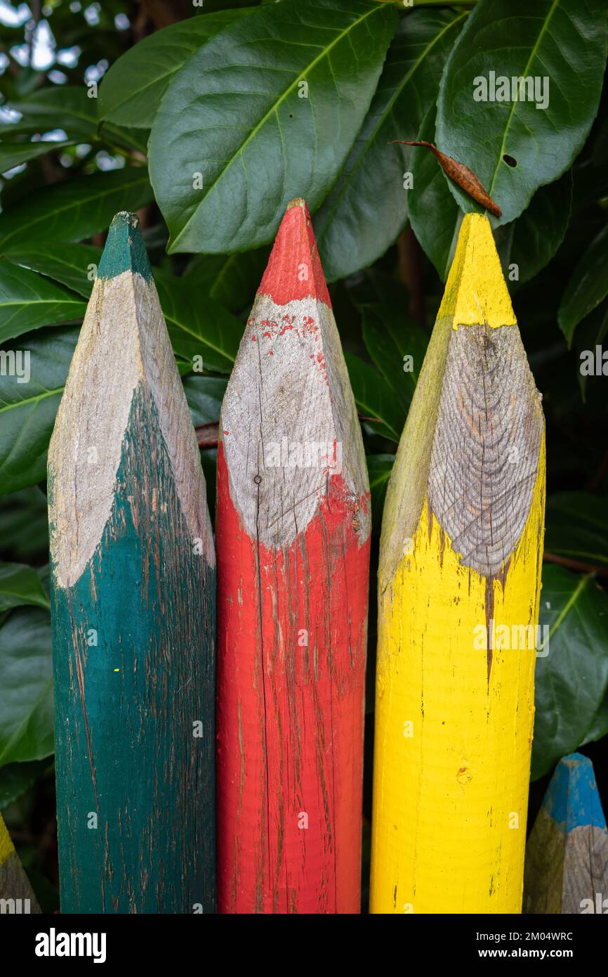 Nahaufnahme eines Gartenzauns in Form von großen bunten Bleistiften in verschiedenen Farben Stockfoto