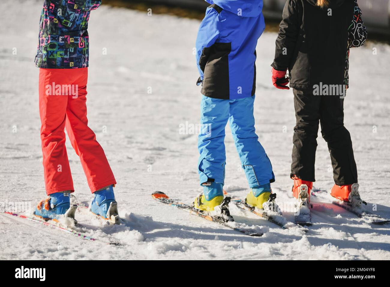 Kinder in Skianzügen fahren Ski auf Schnee Stockfoto