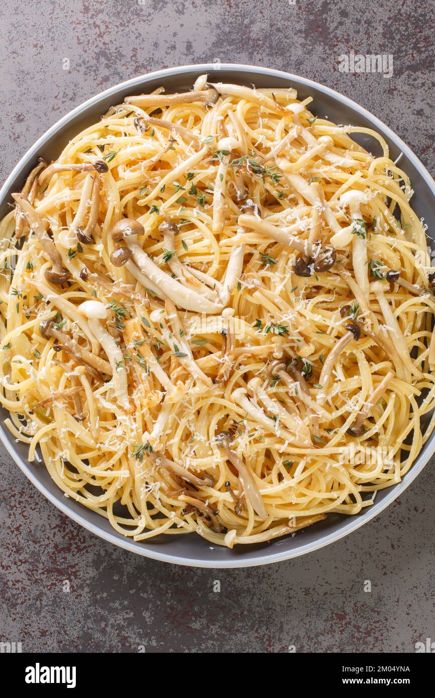 Pasta mit braunen und weißen Buchenpilzen in einer cremigen Pilzsauce und Thymian auf dem Teller. Vertikale Draufsicht von oben Stockfoto