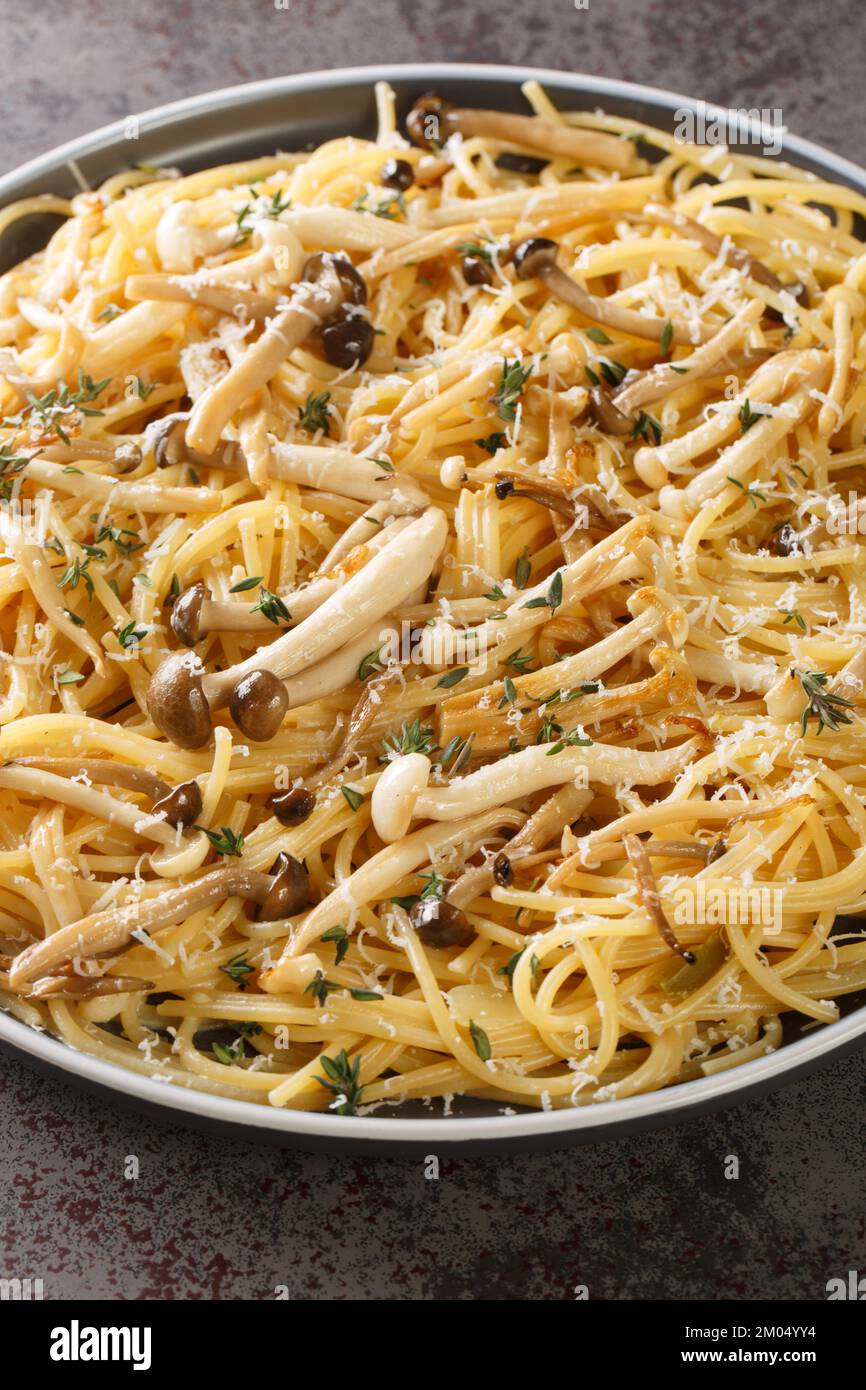 Pasta mit braunen und weißen Buchenpilzen in einer cremigen Pilzsauce und Thymian auf dem Teller. Vertikal Stockfoto