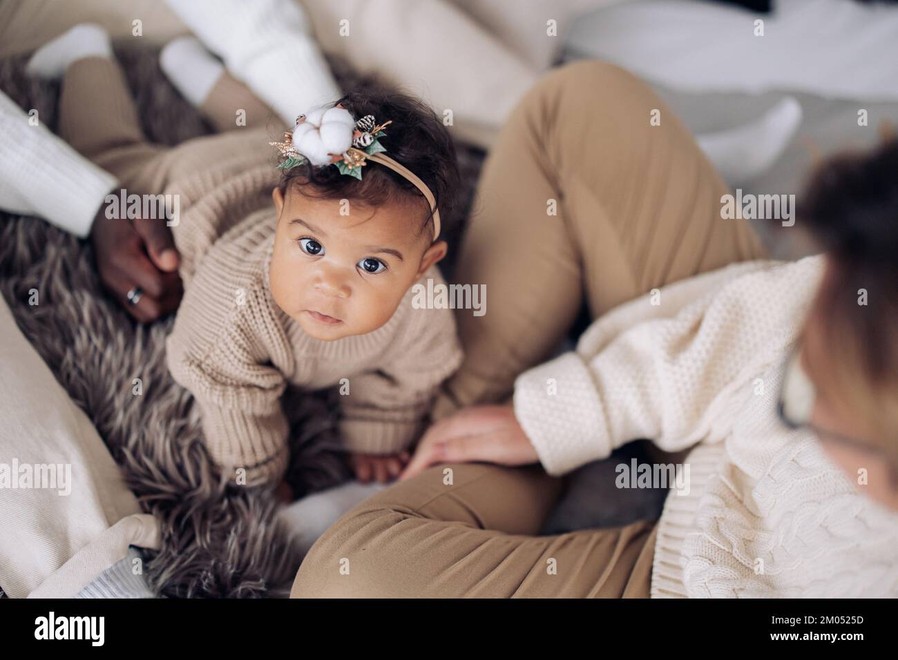 Gemischte Rassen Baby Girl spielt und krabbelt zwischen ihren Eltern. Draufsicht. Der Begriff der zwischenrassischen Familie und die Einheit zwischen verschiedenen menschlichen Rassen. Stockfoto