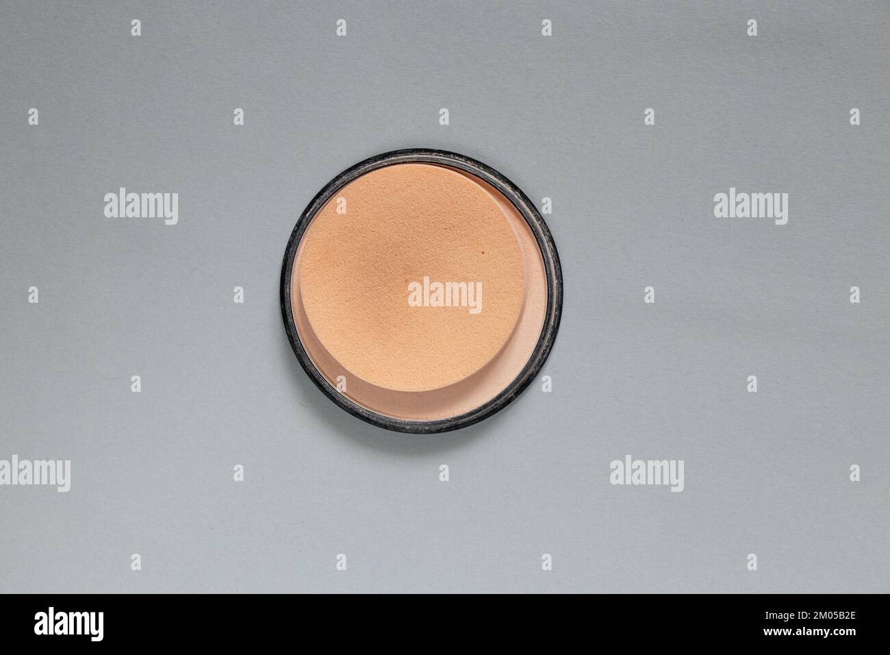 Pulver in einer runden Plastikverpackung auf grauem Hintergrund, Nahaufnahme von Damenkosmetik, Fundamentpulver Stockfoto