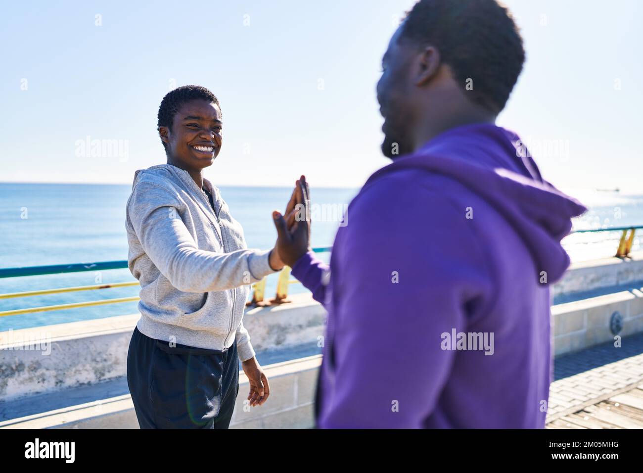 Mann und Frau tragen Sportkleidung mit hohen fünf Händen am Meer angehoben Stockfoto