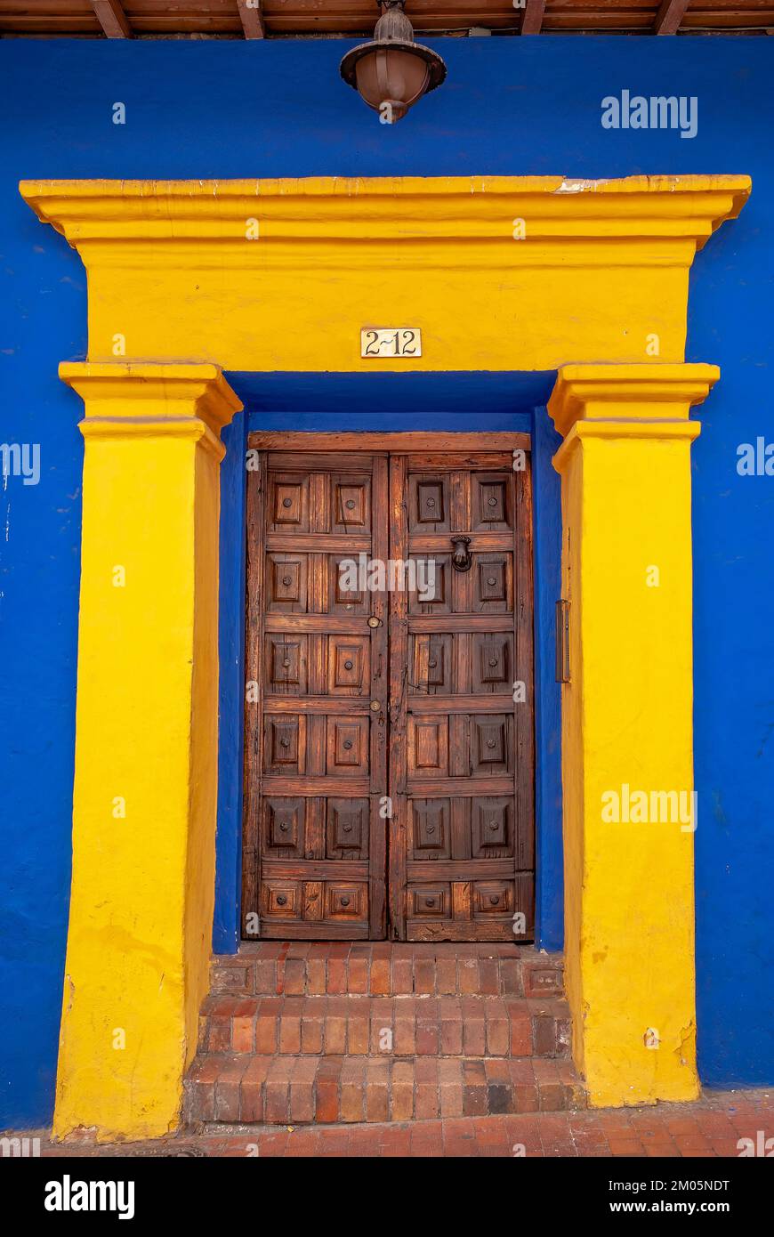 Woodem-Tür in einem gelbblauen Gebäude, La Candelaria, Bogotá, Kolumbien Stockfoto