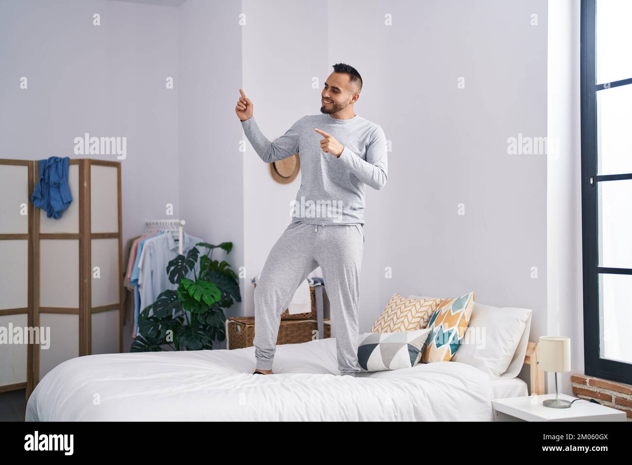 Junger lateinamerikanischer Mann, der im Bett steht und im Schlafzimmer  tanzt Stockfotografie - Alamy