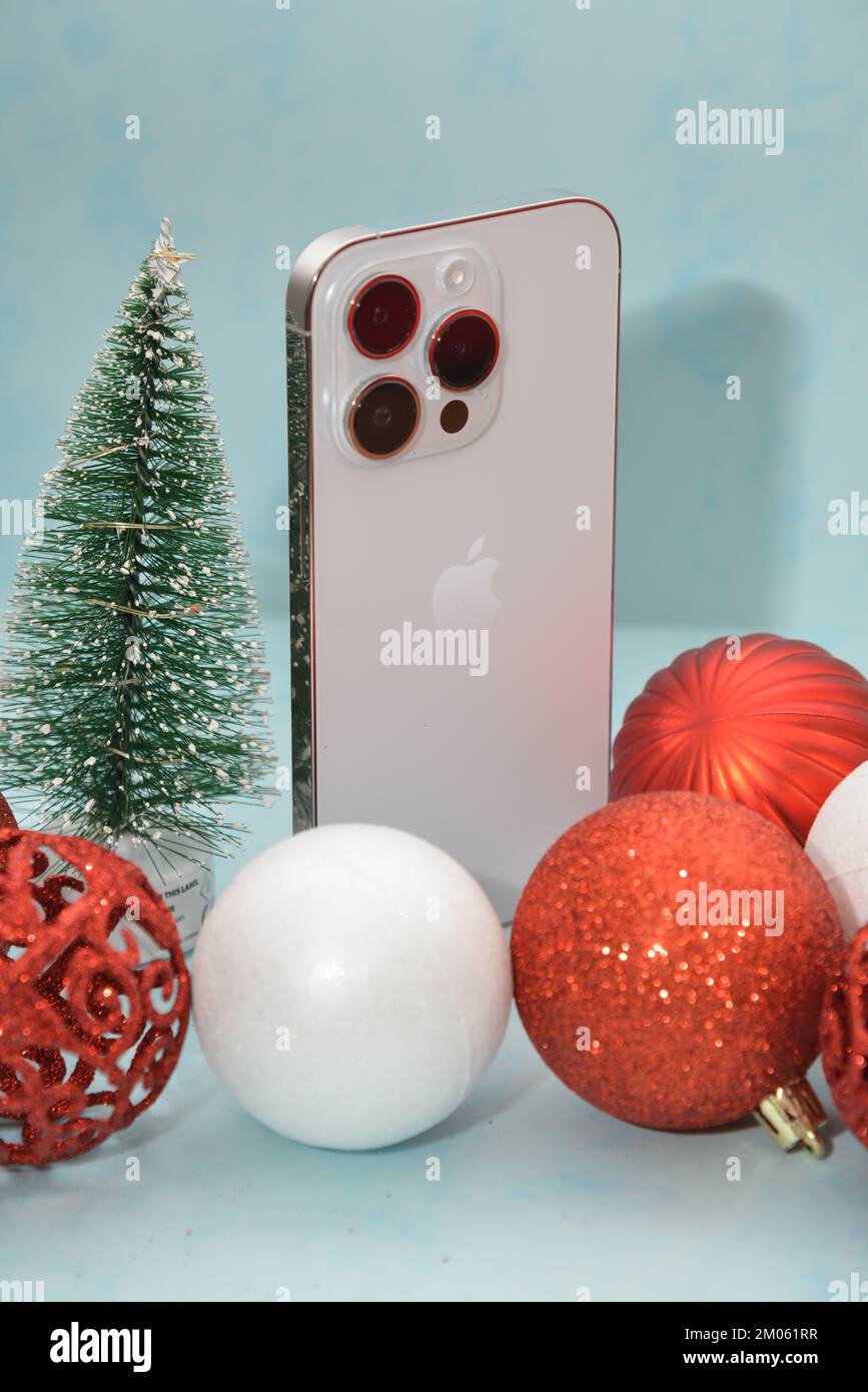 Riga/Lettland - 4. Dezember 2022: Neues modernes Telefon - iPhone 14 pro unter den glitzernden Weihnachtsdekorationen auf schwarzem Hintergrund. Weihnachtsgeschenk Conce Stockfoto